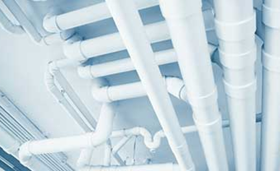 Thick white pipes crisscross the ceiling in multiple directions, forming a complex network.