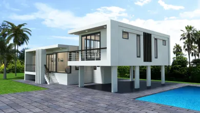 Modern white two-story stilt house with stone patio, in-ground pool, palm trees, and lush greenery under a blue sky.