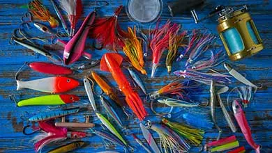 Vibrant fishing lures and tackle spread across a weathered blue wooden surface.