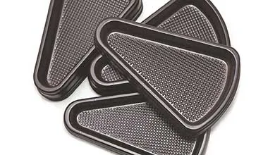 Close-up of several black, triangular plastic trays with dimpled interiors stacked on a white surface.