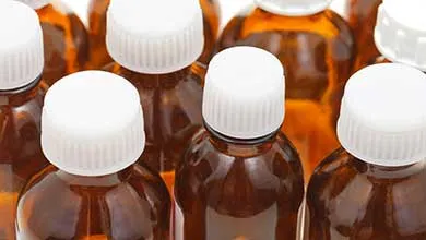 Close-up of brown glass medicine bottles with white ribbed caps.