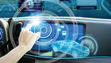 Inside a futuristic car, a person uses a glowing holographic dashboard while driving data is projected onto the windshield above the highway.