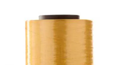 A spool of tightly wound golden-yellow thread with a dark gray or black plastic cap, set against a plain white background.
