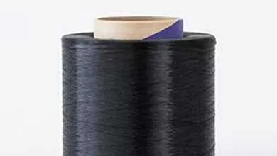 A large cylindrical spool of tightly wound black thread or synthetic filament with a cardboard core featuring a blue stripe at the top, on a plain white background.