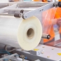 A machine with a large roll of plastic packaging film in a factory