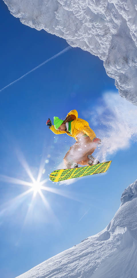 Snowboarder jumping against blue sky